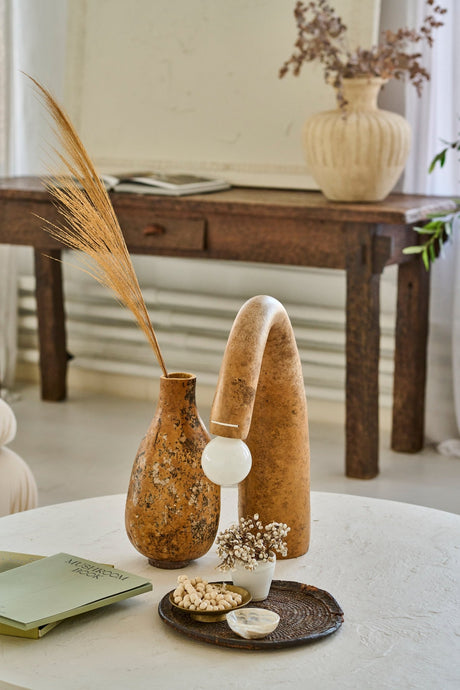 A natural wabi-sabi gourd lamp and a gourd vase stand on a round coffee table with rustic solid wood table at the back.