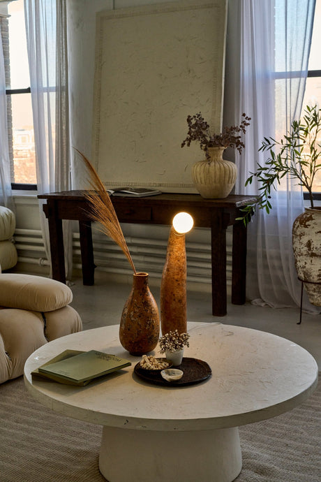A modern spacious living room with a creamy coffee table at the center and a wabi-sabi gourd lamp on the coffee table.